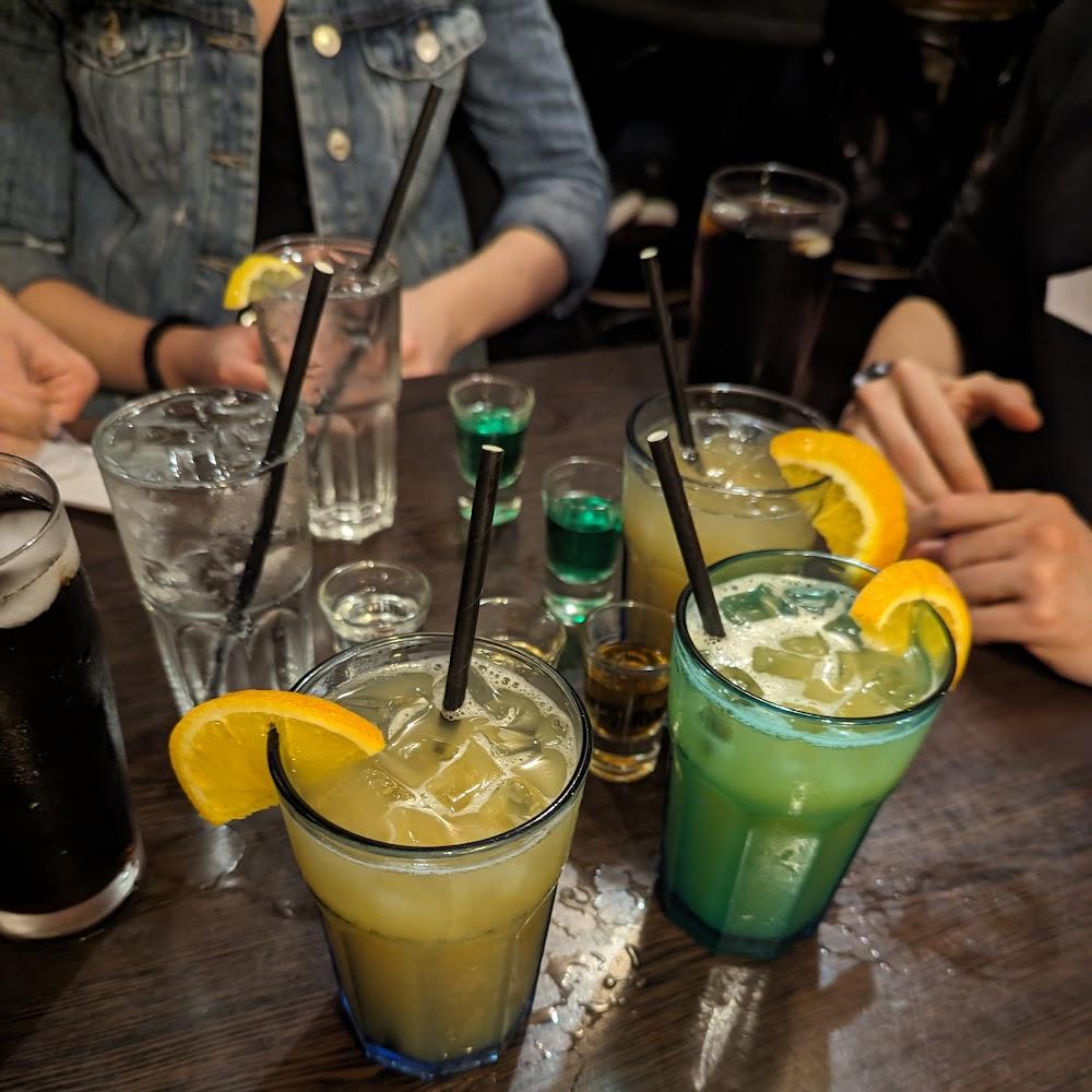 A table with several drinks, including a green drink with a slice of orange.